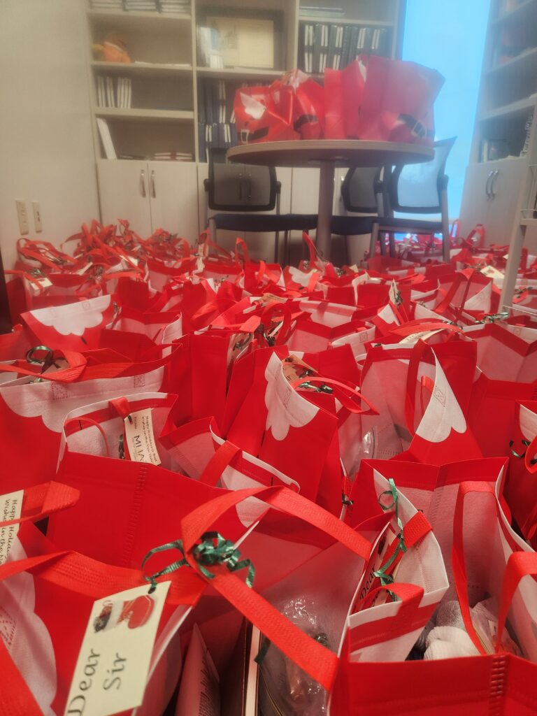 A room filled with bright colored Santa themed gift bags.